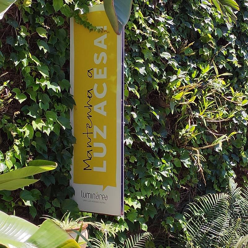 A placa Luz Acesa entre as folhas do jardim